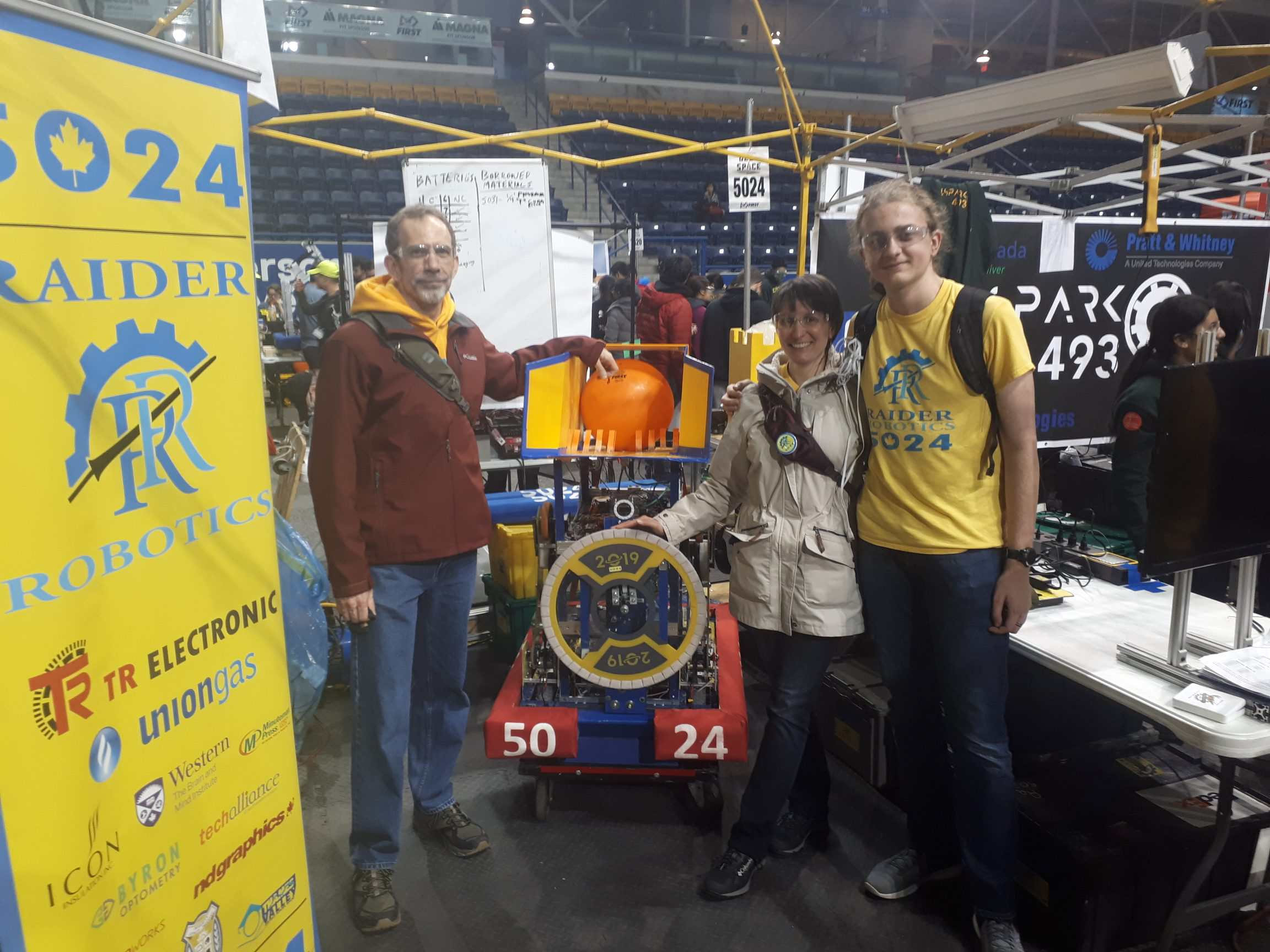 Photo of Gianna with her husband and son and Raider Robotic's 2019 robot